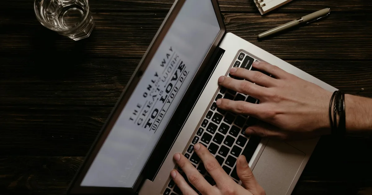 Hands on a laptop with an inspirational quote displayed on the screen, shot from above.