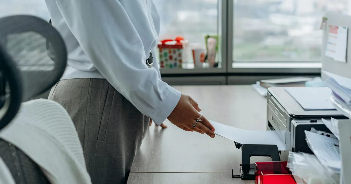 Business professional printing a document in an office environment.