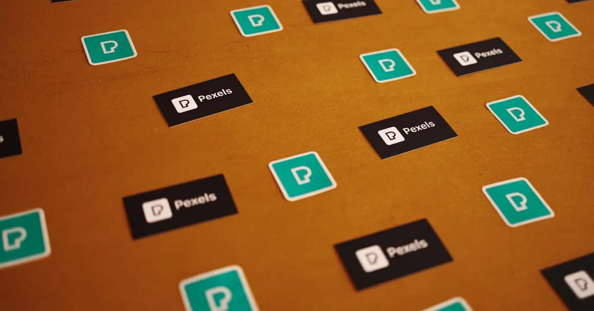 Pexels logos and stickers scattered on a brown background in a creative pattern.