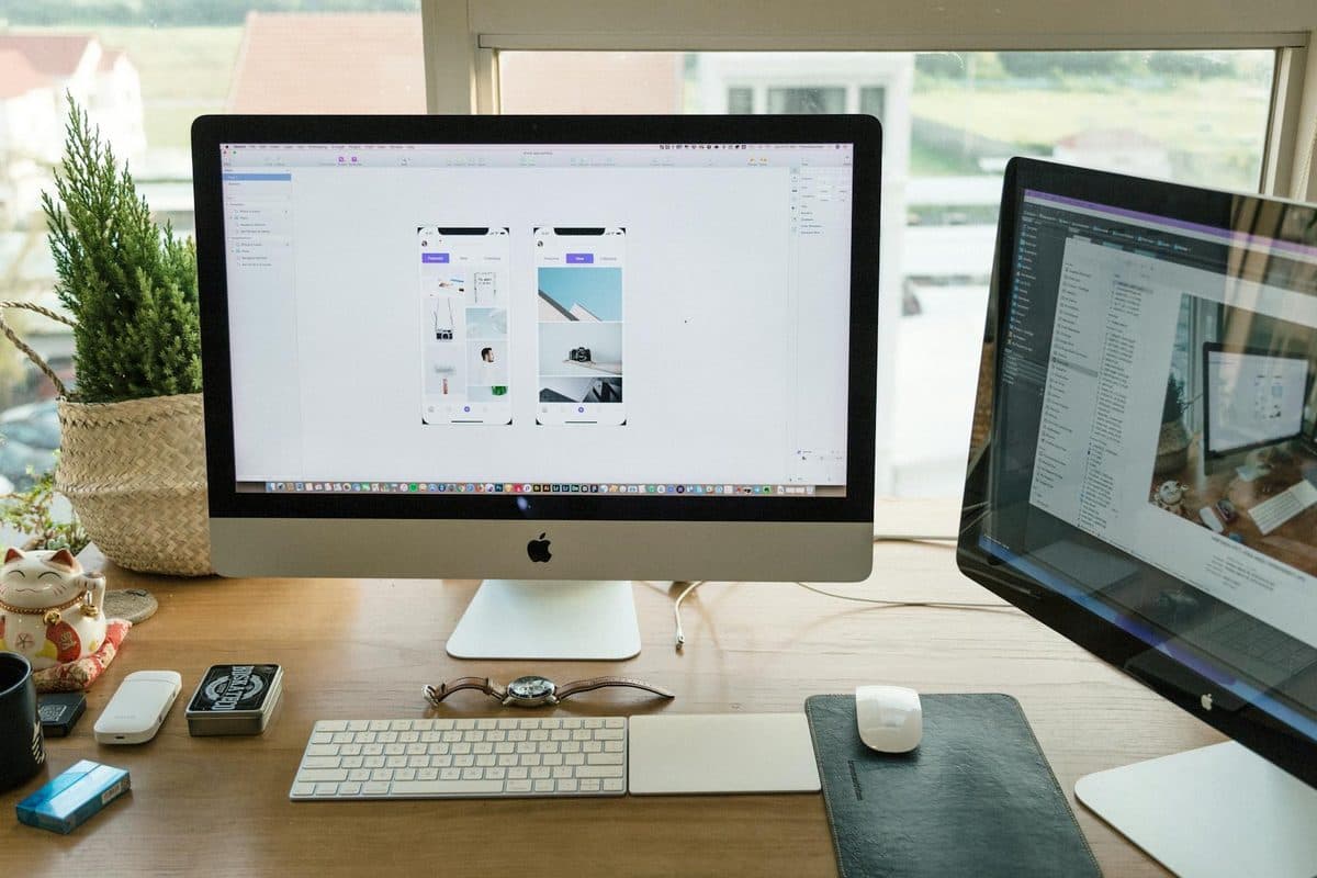 A well-organized modern office setup featuring Apple iMac and multiple monitors in a bright workspace.
