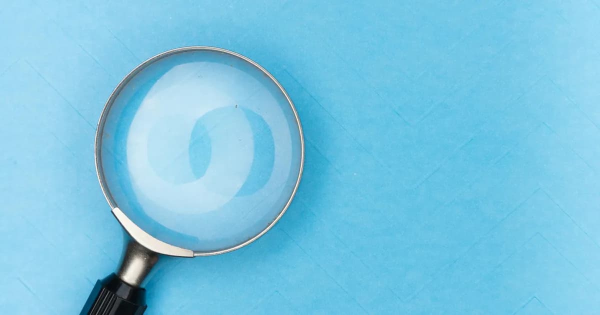 Close-up of a magnifying glass on a blue surface, ideal for search and exploration themes.