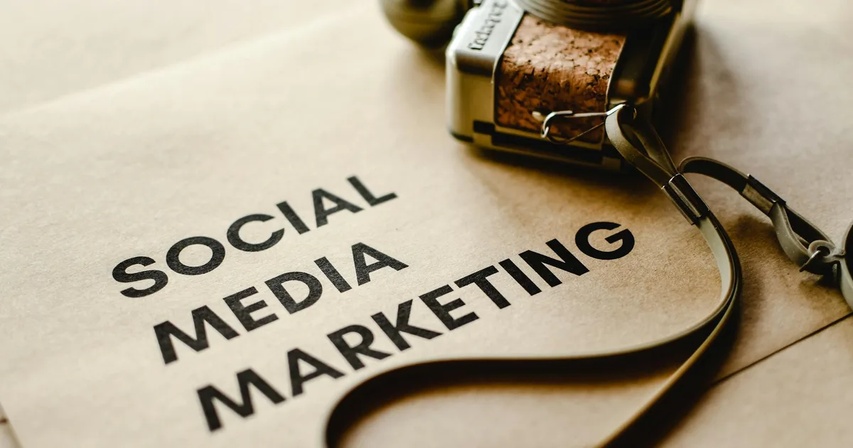 Close-up of a camera placed on brown paper with 'Social Media Marketing' text, emphasizing digital marketing themes.