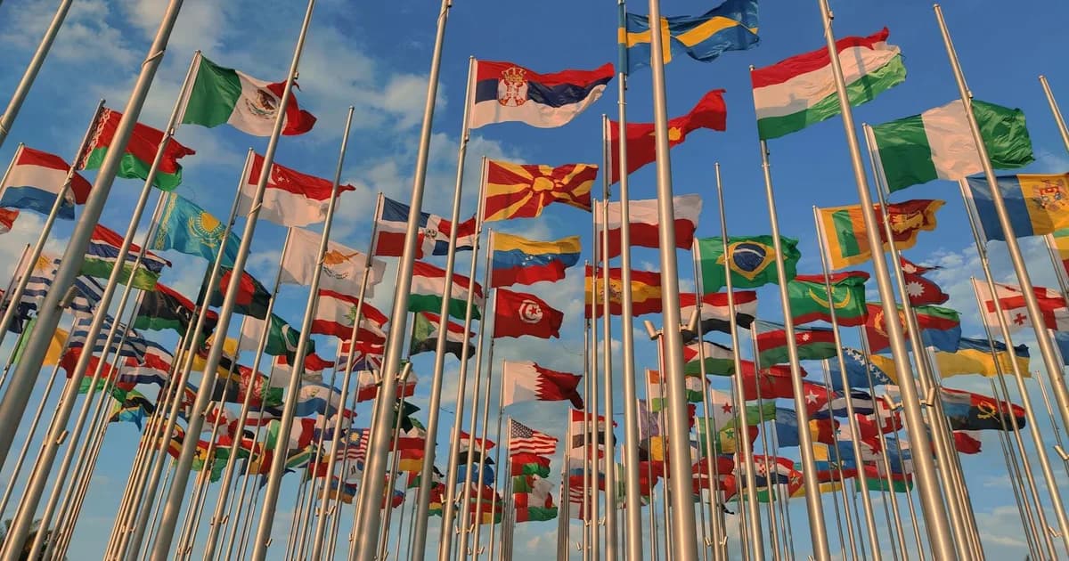 A diverse collection of national flags waving under a vibrant blue sky.