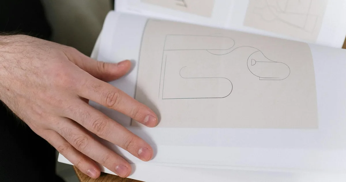 Close-up of a hand flipping through a minimalist abstract art book with geometric designs.