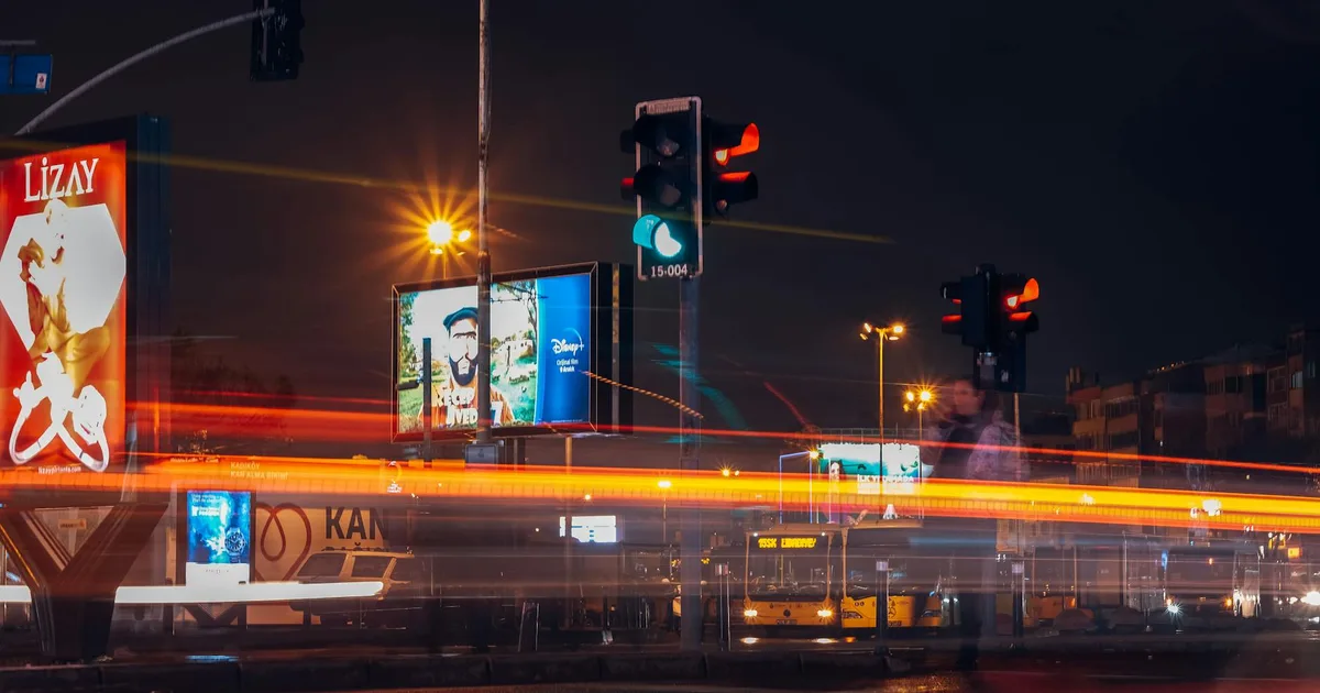 A vibrant city street scene captured at night with long exposure showing traffic lights and light trails.