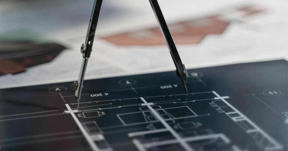 A compass on architectural blueprints, showcasing planning and measurement details.